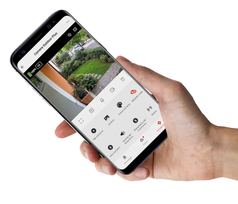 Mano che tiene un cellulare con all'interno la schermata di ripresa della telecamera. Si vede un giuardino